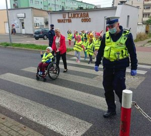 Policjant ruchu drogowego przechodzi wspólnie z dziećmi przez pasy